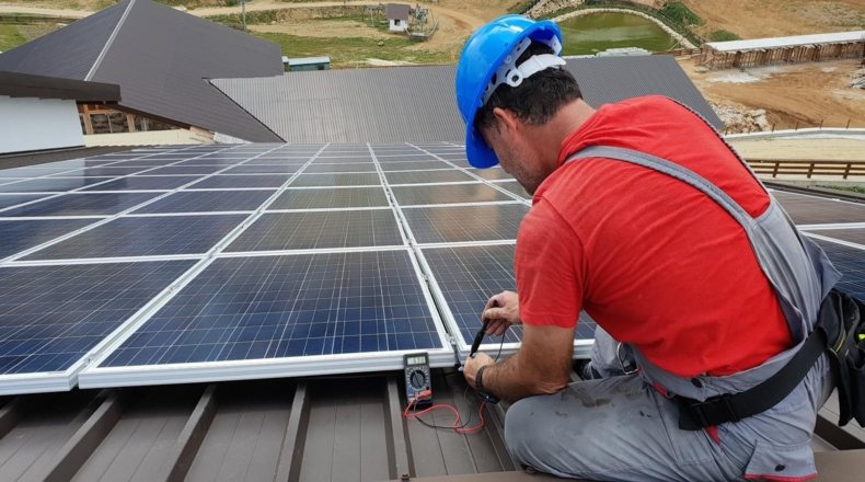 Foto en la que aparece un hombre instalando un panel fotovoltaico
