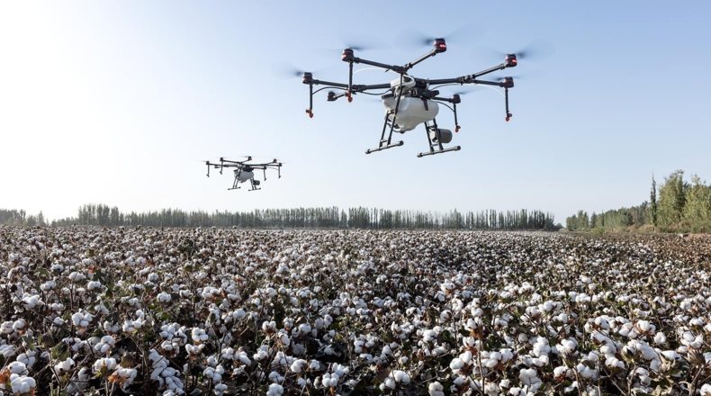 Imagen en la que aparece una explotación agrícola vigilada u observada por dos drones que están en pleno vuelo