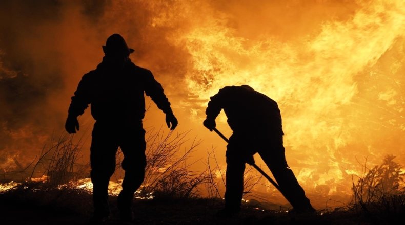 Imagen en la que aparecen miembros de emergencia de protección civil intentando apagar fuego provocado por magma del volcán.