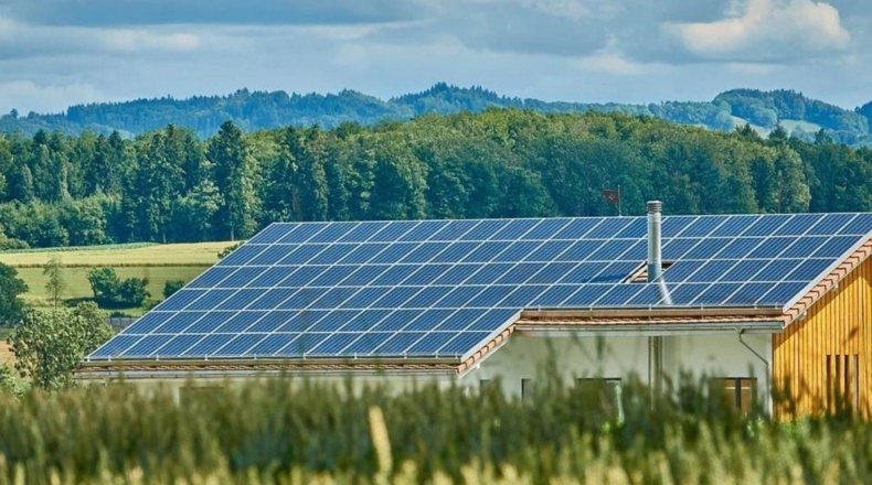 Cómo ahorrar en la factura de la luz instalando placas solares. Imagen de paneles solares situados en la construcción de un terreno rústico, con una buena posición y orientación para obtener mayor rentabilidad y beneficio