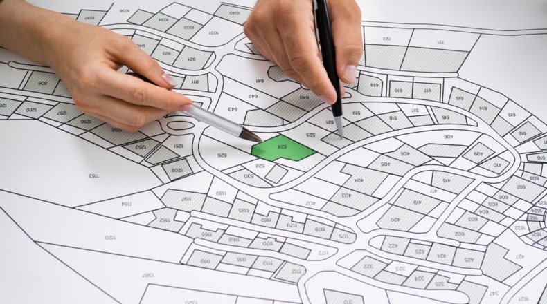 Manos señalando lote en plano de urbanización